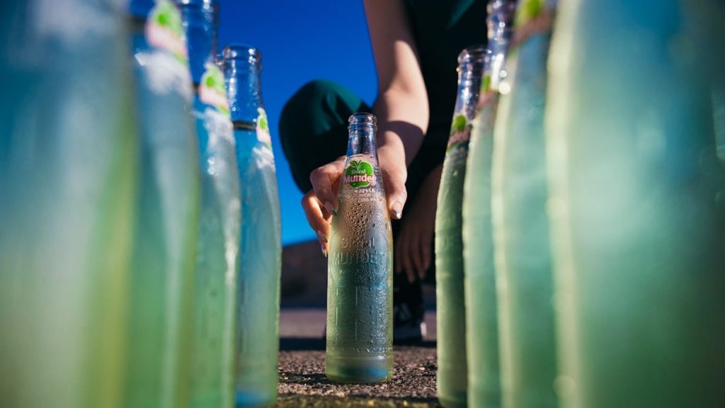 a person kneeling down next to a bunch of bottles